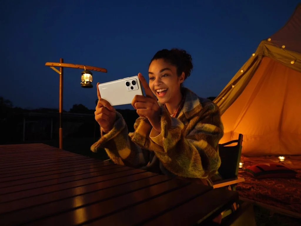Jeune fille souriante en extérieur en soirée, téléphone à la main et casque sur les oreilles, souriant à son téléphone